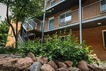 an apartment building with a rock garden in front of it